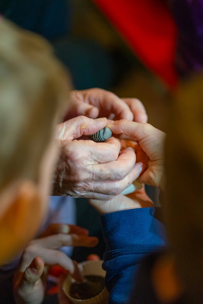 A grandmother and grandchild both hold onto a fossil and observe it within their hands