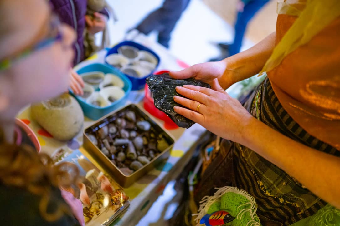 Floss holds a piece of obsidian during a hands on science activity within the mobile science museum 'The Rock Showman's Booth'